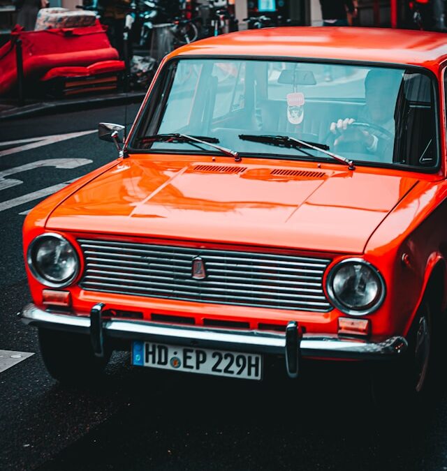 Orange vintage car driving on city street, symbolizing dynamic movement in AI search visibility and LLM optimization context.