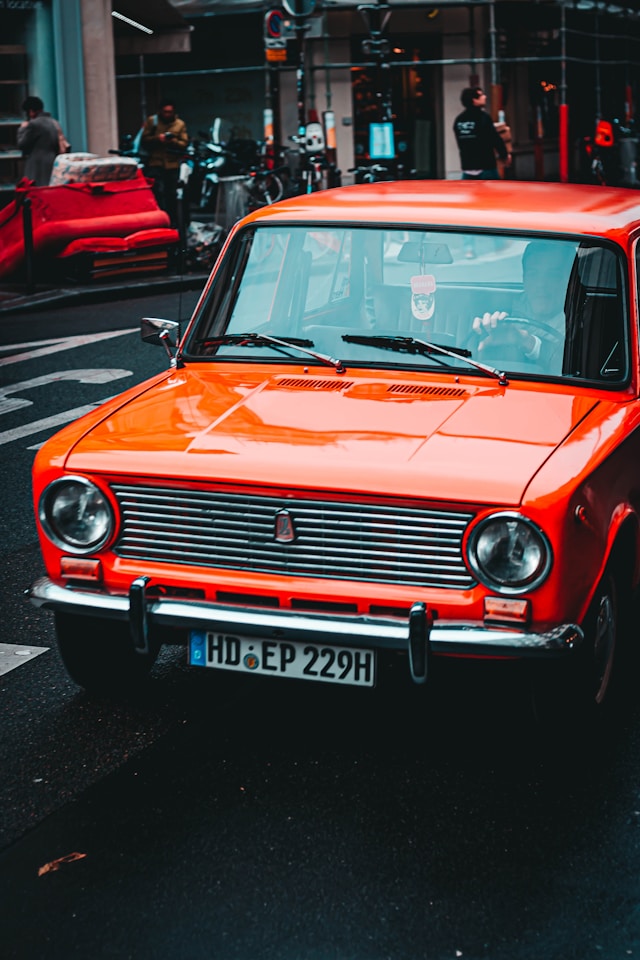 Orange vintage car on urban street, symbolizing innovation and nostalgia in AI-driven business environments.